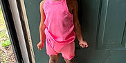Kyrah is registered to the contest to win money with this photo: child, girl, smiling, standing, indoors, door, pink_clothing, shorts, tank_top, white_sneakers, braided_hair, beads, floor, window, natural_light, happy, person, portrait, casual_wear, cute