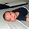 Kenneth joined the competition — help win amazing prizes! baby, infant, child, portrait, lying_down, bed, bedroom, pillow, blanket, onesie, navy_clothing, gray_pants, face, eyes, hair, awake, indoors, home, soft_lighting, photography