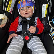 Geo joined the competition — help win amazing prizes! baby, child, helmet, car_seat, smile, pajamas, red_sleeves, striped_pants, plush_toy, safety_harness, cute, infant, indoors, seat_belt, protective_gear, happy, person, closeup, blue_eyes, casual