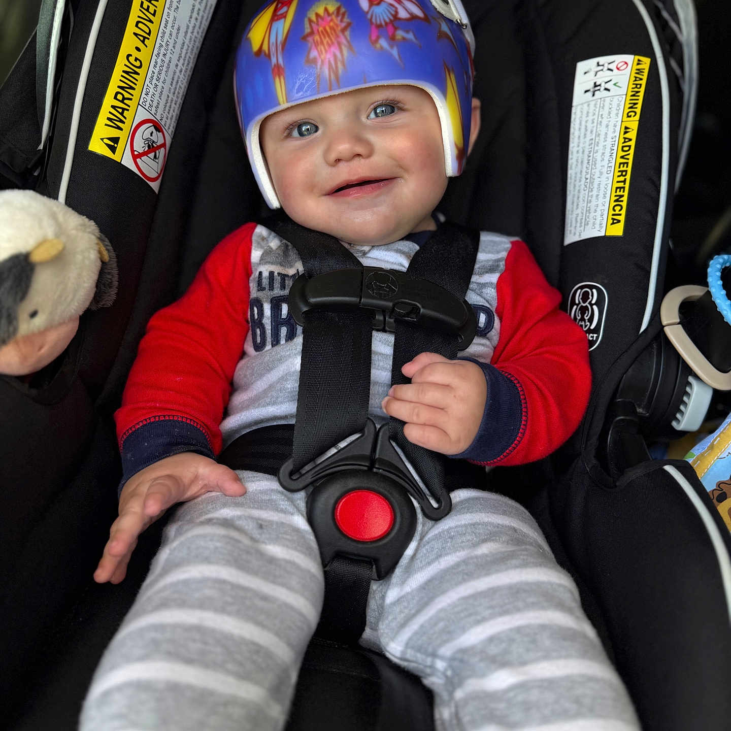 Geo joined the competition — help win amazing prizes! baby, child, helmet, car_seat, smile, pajamas, red_sleeves, striped_pants, plush_toy, safety_harness, cute, infant, indoors, seat_belt, protective_gear, happy, person, closeup, blue_eyes, casual