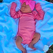 Lydia is registered to the contest to win money with this photo: baby, sleeping, pink_clothing, headband, bow, blanket, outdoor, grass, newborn, infant, cute, peaceful, soft_texture, lying_down, child, portrait, toddler, clothing, person, resting