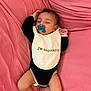 baby, sleeping, pacifier, onesie, bib, pink_bed_sheet, infant, peaceful, child, cute, resting, soft_fabric, hand, foot, skin, face, head, lying_down, indoors, closeup