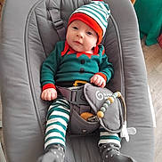 Orlane a rejoint le concours — aidez-le/la à gagner de superbes lots ! accessory, baby, baby_rocker, child, clothing, cute, elf_costume, festive_outfit, gray_fabric, hat, indoor, infant, pacifier, pacifier_clip, person, seated, smiling, striped_clothing, toy, wooden_floor