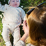 Austin participe au concours pour gagner de l'argent avec cette photo : baby, infant, child, grass, flowers, daisies, knitwear, hat, shoes, adult, woman, sunglasses, hand, nature, outdoor, daylight, greenery, portrait, casual, relaxation