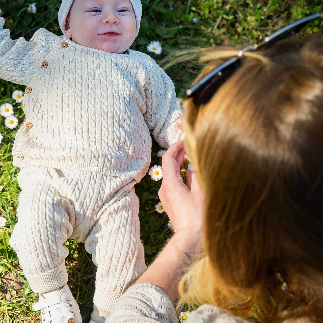 Austin participe au concours pour gagner de l'argent avec cette photo : baby, infant, child, grass, flowers, daisies, knitwear, hat, shoes, adult, woman, sunglasses, hand, nature, outdoor, daylight, greenery, portrait, casual, relaxation