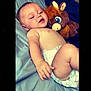 baby, diaper, plush_toy, horse_toy, bed, blue_sheet, smile, child, infant, skin, hand, face, lying_down, relaxed, cute, toy, soft_toy, indoors, person, happy