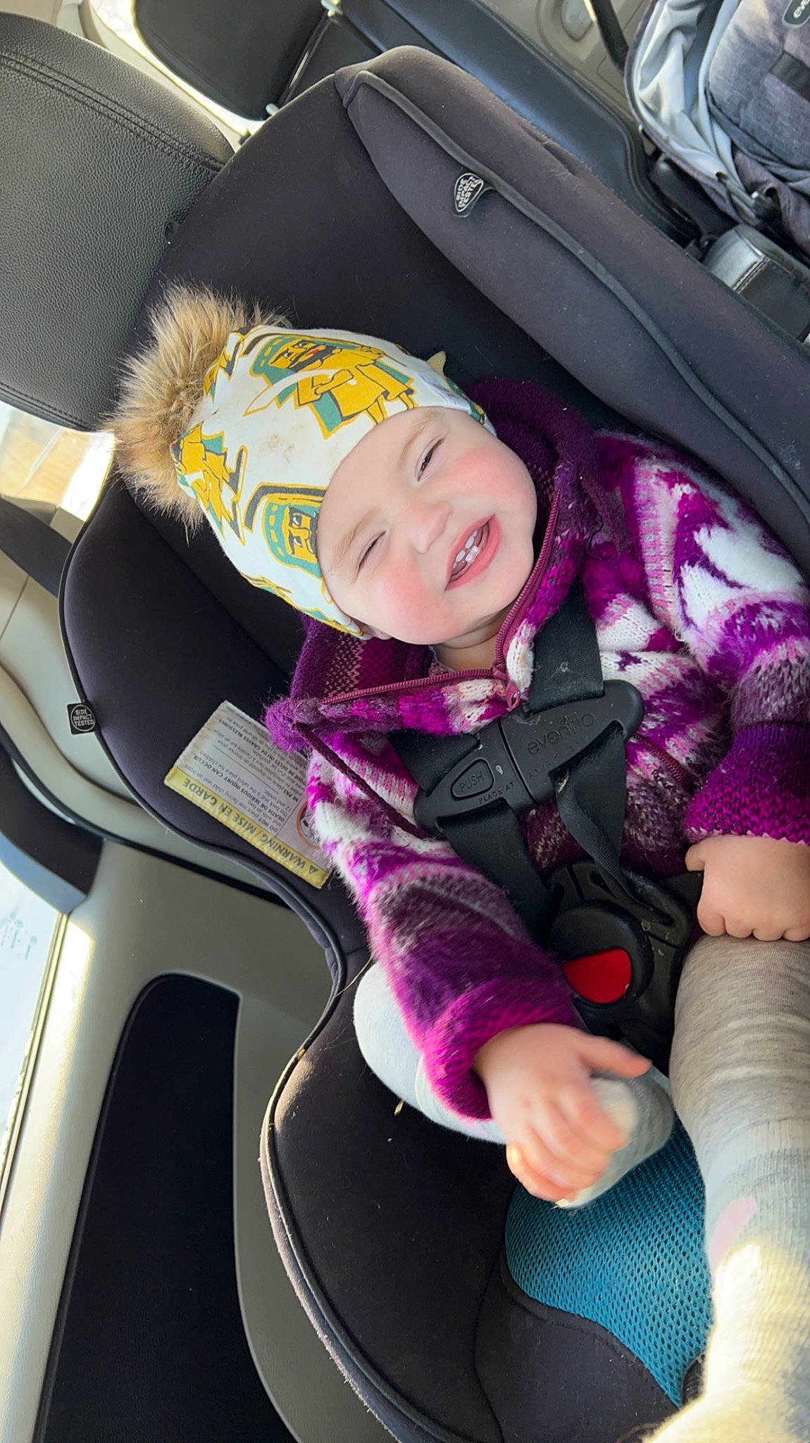 Brenna is registered to the contest to win money with this photo: auto_part, automotive_design, automotive_exterior, baby, baby_carriage, baby_in_car_seat, baby_products, car, car_seat, car_seat_cover, child, comfort, fun, headwear, motor_vehicle, person, smile, steering_part, steering_wheel, toddler