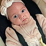 baby, bow, car_seat, child, clothing, cozy, cute, eyes, face, headwear, indoor, infant, newborn, person, pink_clothing, portrait, seatbelt, sitting, soft_texture, straps