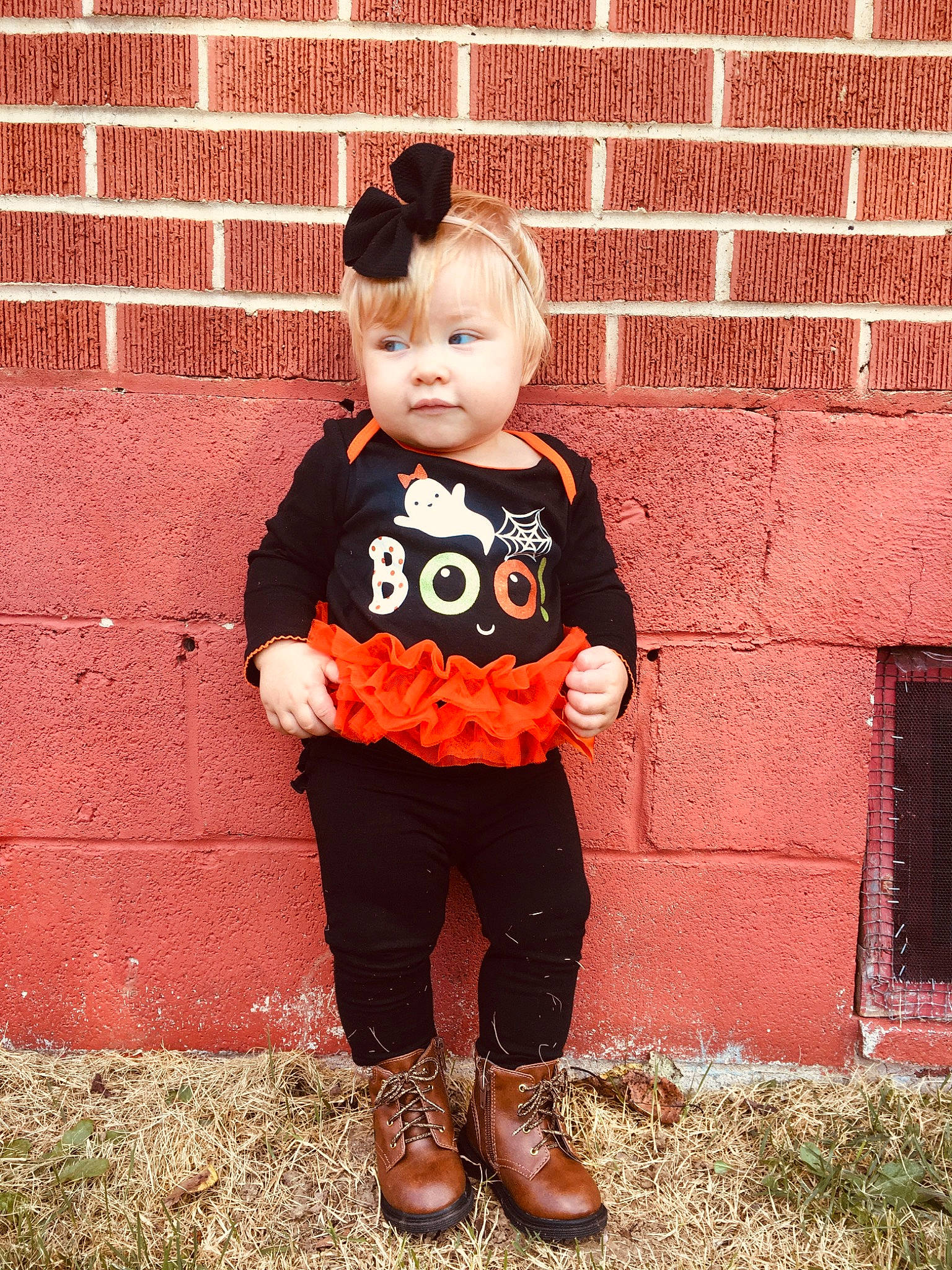 Sienna is registered to the contest to win money with this photo: baby_toddler_clothing, brick, child, cool, footwear, orange, outerwear, pattern, person, shoe, sleeve, smile, standing, t_shirt, toddler