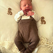 Myles is registered to the contest to win money with this photo: baby, newborn, infant, sleeping, knitwear, brown_clothing, blanket, cream_blanket, dog_motif, soft_texture, hand, cute, peaceful, indoors, portrait, child, cozy, warm, resting, small