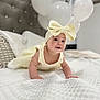 baby, child, crawling, bed, white_bedspread, balloons, headband, bow, dress, pillow, indoor, cute, smiling, happy, infant, portrait, soft_lighting, fabric, celebration, decor