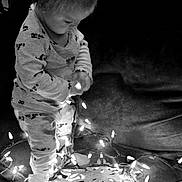 Isaiah is registered to the contest to win money with this photo: black_and_white, child, christmas_lights, couch, cozy, curious, cute, decor, face, holiday, home, illumination, indoor, lights, pajamas, playing, snowflake, string_lights, toddler, young_child