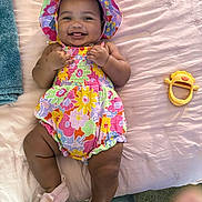 Kaveah joined the competition — help win amazing prizes! baby, infant, child, smiling, happy, portrait, floral_outfit, sun_hat, colorful_clothing, lying_down, bed, blanket, pink, toy, mirror, indoor, home, bare_legs, socks, photography
