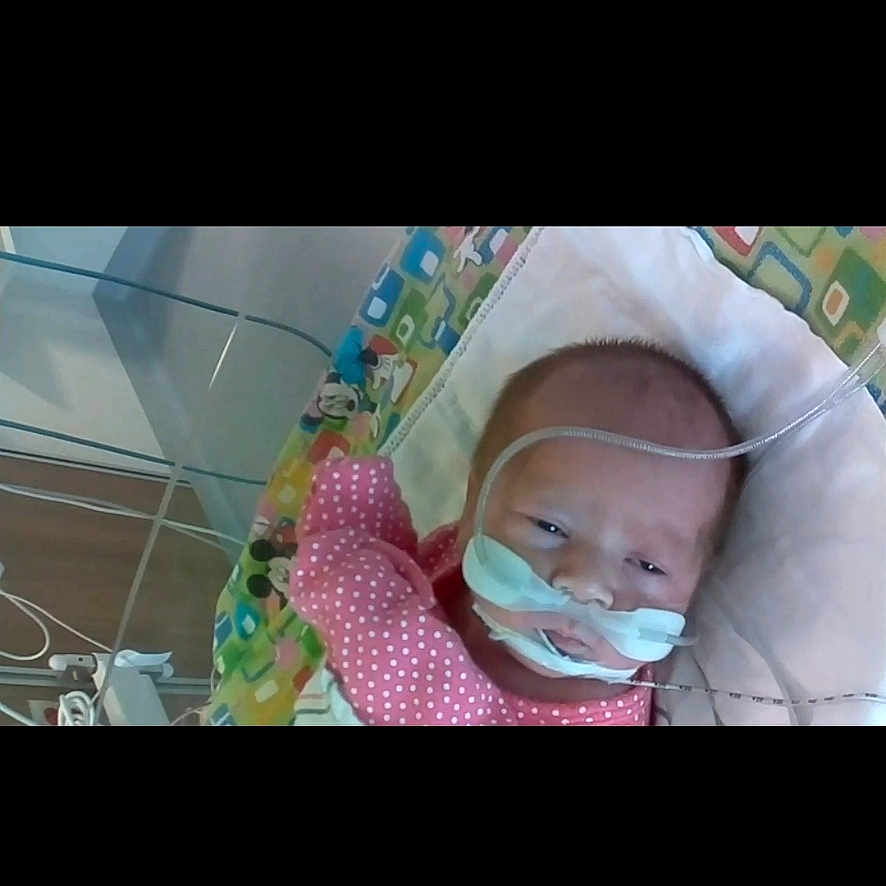 Novalee is registered to the contest to win money with this photo: baby, infant, medical_tubes, hospital, baby_seat, pink_clothing, face, newborn, healthcare, child, person, lying_down, equipment, indoors, monitoring, resting, cute, patient, care, small