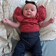 Everleigh joined the competition — help win amazing prizes! baby, infant, headband, bow, red_top, ruffled_sleeves, jeans, denim_pants, bed, pillow, blanket, bedding, cute, smiling, face, eyes, hands, portrait, lying_down, nursery_pattern