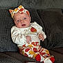 Everleigh is registered to the contest to win money with this photo: baby, infant, newborn, headband, pumpkin_print, onesie, socks, couch, sofa, smartphone, reflection, hands, eyes, surprised_expression, seated, fabric_texture, home_interior, cozy, portrait, holiday_outfit