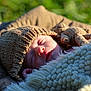 baby, sleeping, knitted_hat, blanket, crocheted_toy, outdoor, sunlight, closeup, face, peaceful, infant, soft_texture, warm, cute, child, portrait, nature, cozy, rest, newborn
