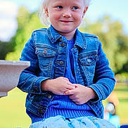 Averiella is registered to the contest to win money with this photo: child, blonde_hair, blue_eyes, denim_jacket, blue_dress, outdoor, bench, smile, portrait, grass, sunny, nature, cute, happy, person, fashion, casual_wear, daylight, park, innocent