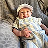 baby, infant, smile, face, cap, clothing, overalls, blanket, fabric, pattern, texture, person, cute, child, soft, resting, indoor, comfort, happy, portrait