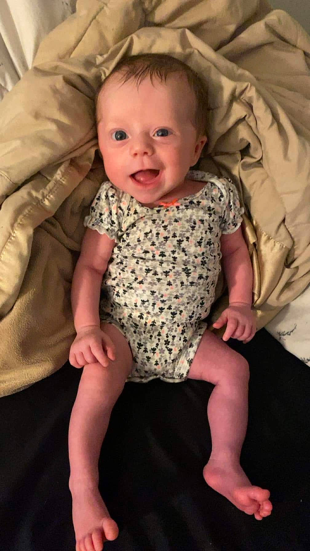 Ella is registered to the contest to win money with this photo: arm, baby, baby_toddler_clothing, cheek, comfort, dress, eye, face, facial_expression, finger, hairstyle, head, human_body, iris, leg, person, pink, skin, sleeve, smile