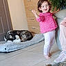 barefoot, cat, child, couch, dog, dresser, floor, happy, home, husky, indoor, living_room, person, pink_shirt, plant, sleeping_dog, smiling, tabby_cat, tile_floor, toddler