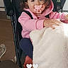 Luuna a rejoint le concours — aidez-le/la à gagner de superbes lots ! baby, blanket, casual, child, clothing, comfort, cozy, curly_hair, cute, face, indoor, looking_at_camera, pacifier, person, pink_hoodie, seated, soft_texture, stroller, toddler, young_child