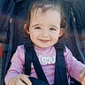 baby, child, closeup, clothing, daylight, face, hair_tied, hand, happy, lens_flare, outdoor, person, pink_shirt, portrait, seat, seatbelt, smile, stroller, sunlight, toddler