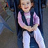 baby, casual, child, concrete, curly_hair, cute, daylight, happy, outdoor, person, pink_clothing, plastic_chair, playful, portrait, seat_belt, sitting, smile, stroller, toddler, young_child