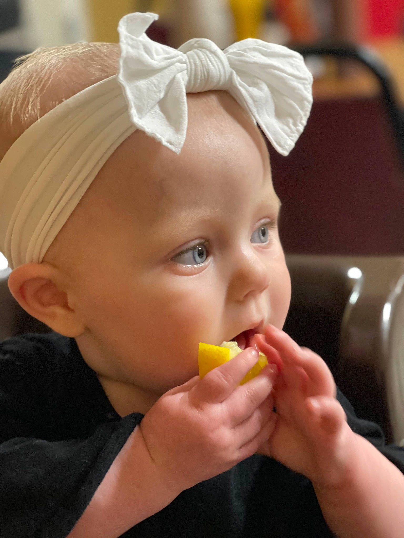 Mckinley is registered to the contest to win money with this photo: baby, biting, cheek, child, ear, eyebrow, eyelash, food, hairstyle, headband, headpiece, lip, mouth, neck, nose, orange, person, skin, sweetness, toddler