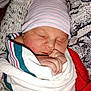 Richmond is registered to the contest to win money with this photo: newborn, baby, sleeping, hat, blanket, swaddled, infant, face, hand, cozy, warm, patterned, striped, closeup, soft, cute, person, rest, comfort, toddler