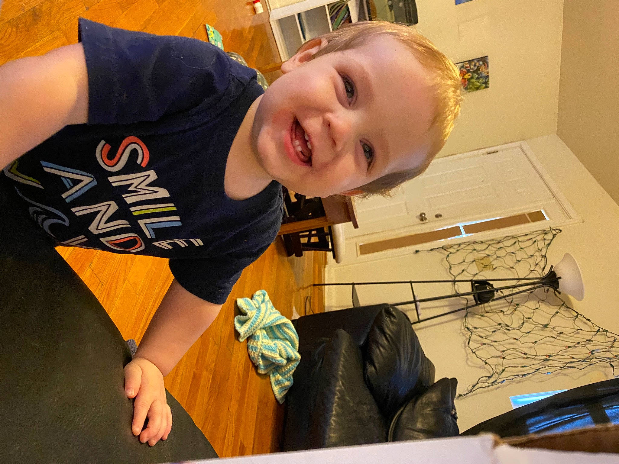 Ronin is registered to the contest to win money with this photo: bag, child, elbow, flooring, fun, happy, human_leg, joy, knee, laugh, leisure, person, play, room, sitting, sleeve, smile, sportswear, t_shirt, thigh