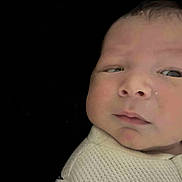 Julius is registered to the contest to win money with this photo: baby, infant, face, closeup, expression, clothing, white, texture, skin, head, newborn, portrait, young, child, person, eyes, nose, mouth, black_background, babywear