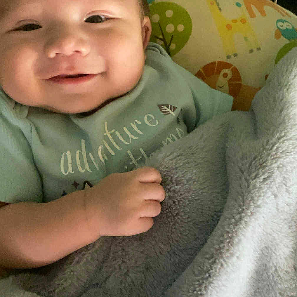 Kizer is registered to the contest to win money with this photo: animal_pattern, baby, bed, blanket, child, clothing, comfort, cozy, cute, face, green_background, hand, happy, indoors, infant, pillow, resting, smile, soft, wrapped