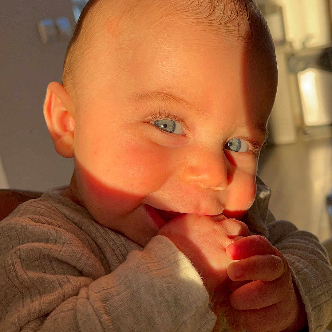 Lyam a rejoint le concours — aidez-le/la à gagner de superbes lots ! baby, blue_eyes, casual, child, close_up, clothing, cute, face, hand, happy, indoor, infant, light, long_sleeve, playful, portrait, shadow, skin, smiling, warm_light