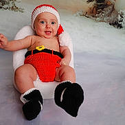 Cameron a rejoint le concours — aidez-le/la à gagner de superbes lots ! baby, infant, smile, santa_hat, knitted_clothing, red_outfit, black_booties, chair, holiday_theme, winter, snow, background, festive, cute, portrait, child, happy, indoors, seasonal, celebration