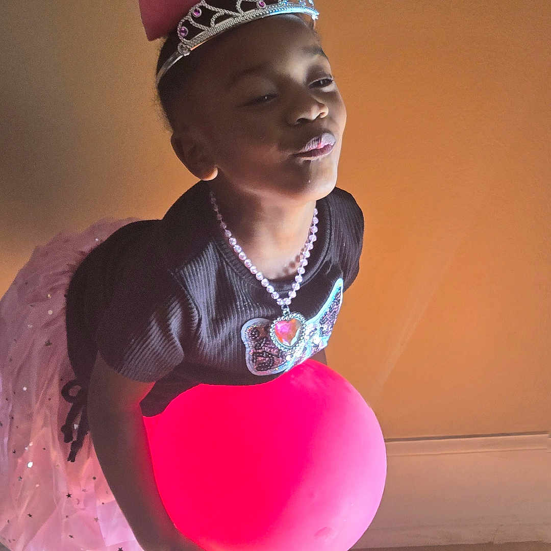 Tevaeh is registered to the contest to win money with this photo: accessories, balloon, child, clothing, dress, face, female, footwear, girl, head, jewelry, necklace, person, photography, portrait, purple, shoe, sphere, tiara, wood