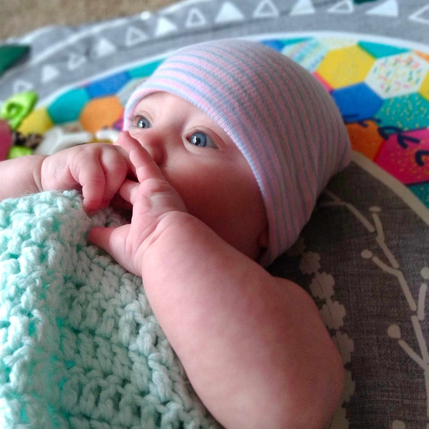 Adalene is registered to the contest to win money with this photo: art, baby, blue, cap, child, close_up, comfort, finger, gesture, headgear, linens, mammal, mouth, nail, pattern, skin, textile, thumb, toddler, wool
