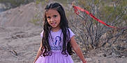 Gabriella is registered to the contest to win money with this photo: bushes, casual, child, desert, dress, girl, happy, long_hair, nature, outdoor, person, playful, portrait, purple, red_tape, sand, smile, standing, sunset_light, young