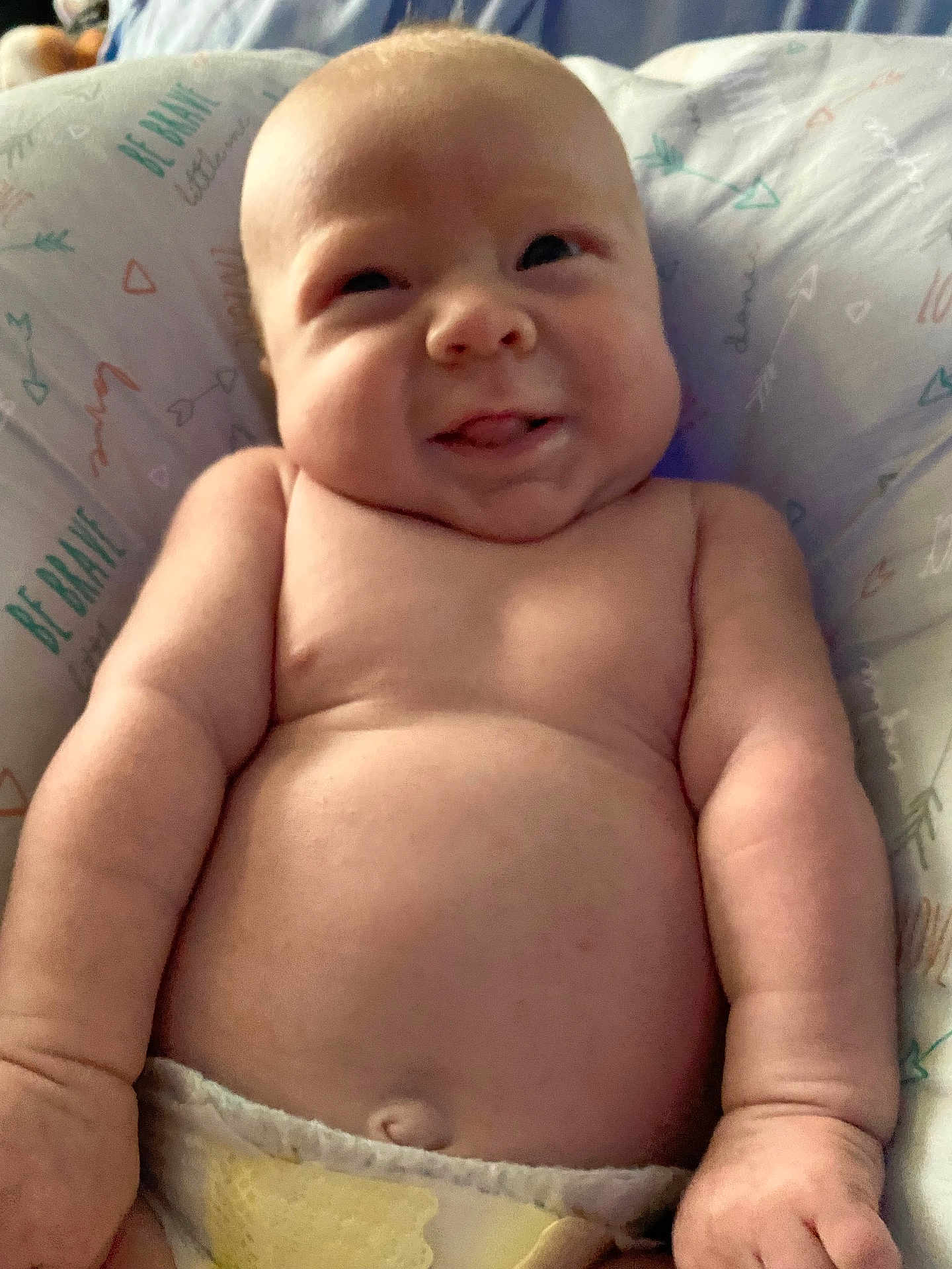 Wayden joined the competition — help win amazing prizes! baby, infant, smile, tongue, bare_chest, diaper, chubby, cute, face, skin, arm, hand, pillow, pattern, text, comfort, lying_down, closeup, portrait, child