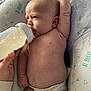 baby, infant, bottle, feeding, diaper, hand, pillow, pattern, arrows, text, love, be_brave, lying_down, skin, arm, face, head, person, indoor, closeup