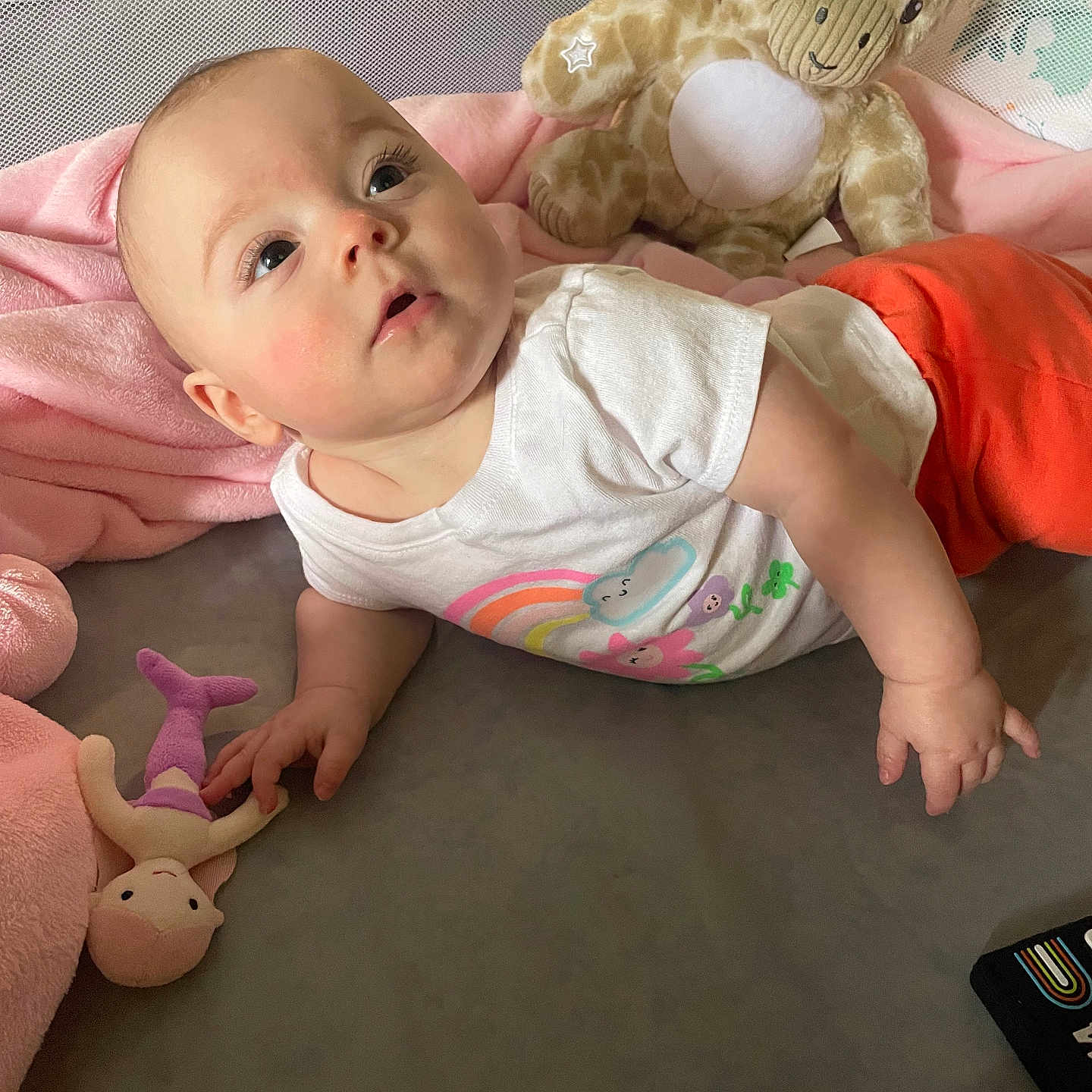Amelia joined the competition — help win amazing prizes! baby, bed, blanket, child, cute, expression, face, hand, indoor, infant, laying_down, looking_up, mermaid_doll, orange_pants, pink_blanket, plush_giraffe, skin, soft_toys, toy, white_shirt