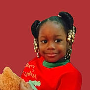 Genesis is registered to the contest to win money with this photo: child, smile, girl, braids, beads, red_sweater, plush_toy, teddy_bear, holiday_clothing, portrait, indoor, cute, festive, happy, person, face, holding, toy, background, young