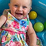 Skylar is registered to the contest to win money with this photo: baby, child, smiling, dress, floral_pattern, inflatable_pool, plastic_balls, yellow_ball, green_ball, happy, cute, infant, sitting, playful, indoors, colorful, cheerful, portrait, hand, face