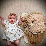 baby, infant, dress, headband, carpet, plush, lion, wall_decoration, soft_texture, giraffe_pattern, child, cute, indoors, portrait, smile, happy, person, toy, animal, floor