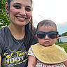Jolynn joined the competition — help win amazing prizes! woman, baby, sunglasses, bib, smile, outdoor, greenery, tree, grass, casual_clothing, portrait, headshot, person, happy, cute, summer, sunlight, accessory, parent, child