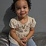 Nyla May joined the competition — help win amazing prizes! child, toddler, curly_hair, smiling, sitting, jeans, embroidered_top, indoor, gray_wall, portrait, cute, young_child, casual_clothing, happy, person, fashion, innocence, skin, face, hands