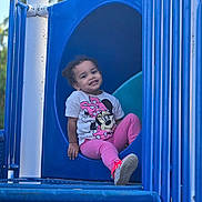 Nyla May joined the competition — help win amazing prizes! toddler, child, playground, slide, blue, pink_clothing, minnie_mouse, smiling, sitting, outdoor, play, happy, casual, cute, person, young_child, fun, daytime, leisure, park