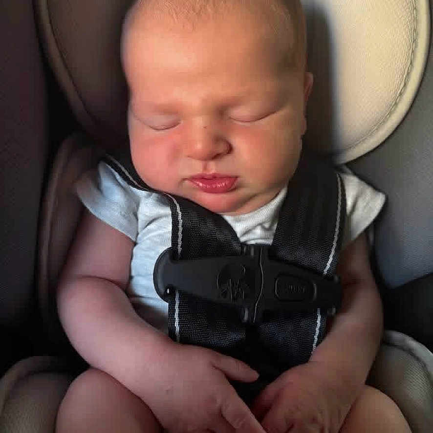 Kastyn joined the competition — help win amazing prizes! baby, infant, sleeping, car_seat, seatbelt, harness, portrait, face, eyes_closed, indoors, vehicle, sitting, hands, arms, legs, clothing, white_shirt, cozy, photography, child