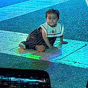 Ophelia is registered to the contest to win money with this photo: child, baby, floor, tiles, blue_light, green_light, sitting, striped_clothing, outdoor, night, curious, person, footwear, candid, cute, young, face, hand, pavement, colorful