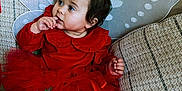 Ophelia joined the competition — help win amazing prizes! toddler, child, red_dress, fairy_wings, couch, cushions, indoors, sitting, curious, finger_in_mouth, hair_bow, cute, portrait, fabric, home, cozy, soft_lighting, baby, person, expression